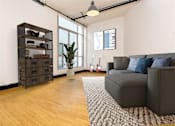 Thumbnail 3 of 37 - Dog-Friendly Apartments in Downtown Los Angeles, CA - Mercantile Lofts - Cozy Living Room With Bamboo Wood Flooring, Floor-to-Ceiling Windows with Beautiful Natural Light, And City Skyline Views.