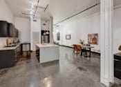Thumbnail 24 of 37 - a kitchen and dining room with white walls and concrete floors