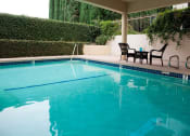 Thumbnail 8 of 12 - the pool is next to a patio with chairs and a table