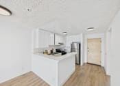 Thumbnail 28 of 46 - A kitchen with white cabinets and a wooden floor.