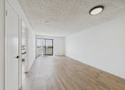 Thumbnail 34 of 46 - A room with a white ceiling and wooden flooring with a door on the left.