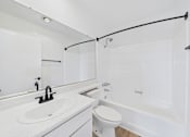 Thumbnail 36 of 46 - A white bathroom with a sink, toilet, and bathtub.