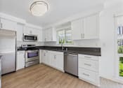 Thumbnail 103 of 135 - A kitchen with white cabinets and a black countertop.