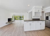 Thumbnail 107 of 135 - A modern kitchen with white cabinets and a wooden floor.