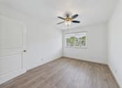 Thumbnail 116 of 135 - A room with a ceiling fan and a window showing a view of trees.