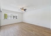 Thumbnail 114 of 135 - A room with a ceiling fan and light fixture, a window with blinds, and wooden flooring.