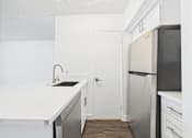 Thumbnail 32 of 88 - A kitchen with a white counter top and a black refrigerator.