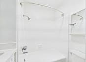 Thumbnail 35 of 88 - A white bathroom with a tub, sink, and shower.