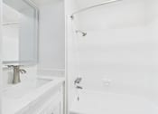Thumbnail 36 of 88 - A white bathroom with a sink, mirror, and bathtub.