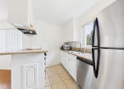Thumbnail 25 of 88 - A kitchen with a stainless steel refrigerator and white cabinets.