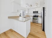 Thumbnail 116 of 208 - A kitchen with white cabinets and a wooden island.