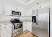 Thumbnail 115 of 208 - A kitchen with a stainless steel refrigerator, microwave, oven, and cabinets.