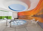 Thumbnail 75 of 77 - A hot tub in a room with a mural of a sunset.
