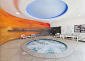 Thumbnail 76 of 77 - A hot tub in a room with a sunset mural on the wall.