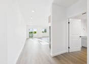 Thumbnail 15 of 22 - A long white hallway with a door on the right.