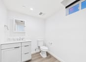 Thumbnail 21 of 22 - A white bathroom with a toilet, sink, and mirror.