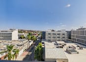 Thumbnail 98 of 163 - A view of a cityscape with buildings, roads, and palm trees.