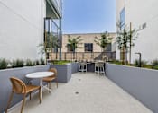 Thumbnail 97 of 163 - A patio with a table and chairs overlooks a building.