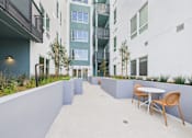 Thumbnail 104 of 163 - A patio with a table and chairs is surrounded by buildings.