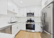 Thumbnail 14 of 28 - A modern kitchen with stainless steel appliances and white cabinets.