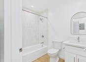 Thumbnail 16 of 28 - A white bathroom with a toilet, sink, and bathtub.