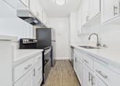Thumbnail 44 of 45 - A kitchen with white cabinets and a black stove top oven.