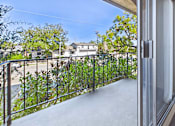 Thumbnail 32 of 45 - A balcony with a metal railing and a view of a street and houses.