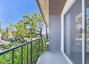 Thumbnail 31 of 45 - A balcony with a metal railing and glass doors overlooking a garden.