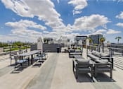 Thumbnail 36 of 44 - A rooftop patio with a table and chairs overlooking a city skyline.