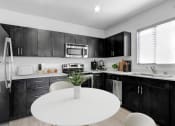 Thumbnail 11 of 22 - a kitchen with black cabinets and a white table