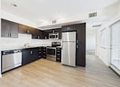Thumbnail 18 of 33 - A modern kitchen with black cabinets and stainless steel appliances.