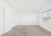 Thumbnail 24 of 33 - A room with a carpeted floor and a window with blinds.