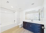 Thumbnail 28 of 33 - A white bathroom with a blue cabinet.