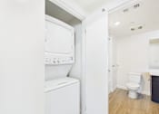 Thumbnail 27 of 33 - A white washing machine is in a small laundry room.