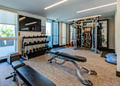 Thumbnail 22 of 35 - A gym with a variety of equipment including weights, a bench, and a leg press machine.