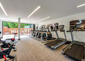 Thumbnail 26 of 35 - A gym with treadmills and a view of an outdoor area.