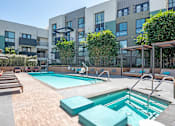 Thumbnail 21 of 35 - A large outdoor swimming pool surrounded by wooden decking and sun loungers.