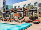 Thumbnail 34 of 35 - A poolside area with lounge chairs and umbrellas.