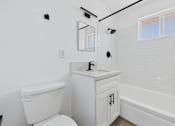Thumbnail 11 of 12 - A white bathroom with a toilet, sink, and bathtub.