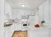 Thumbnail 1 of 17 - A kitchen with white cabinets and appliances.
