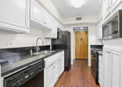 Thumbnail 1 of 15 - a kitchen with white cabinets and black appliances and a door to a hallway