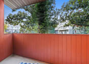 Thumbnail 4 of 15 - a balcony with a red privacy wall and trees