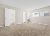 Thumbnail 5 of 15 - the spacious living room of an apartment with carpet and an open door to the bathroom