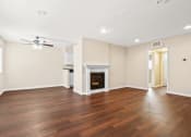Thumbnail 13 of 15 - an empty living room with a fireplace and a ceiling fan