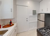 Thumbnail 16 of 21 - A kitchen with white cabinets and a black stove top.