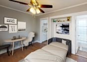 Thumbnail 13 of 21 - A bedroom with a bed, a table, chairs, and a ceiling fan.