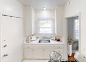 Thumbnail 1 of 21 - A white kitchen with a sink and a window.