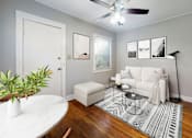 Thumbnail 4 of 21 - A living room with a white couch, a plant, and pictures on the wall.
