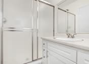 Thumbnail 6 of 17 - A white bathroom with a sink and a shower.