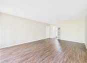 Thumbnail 16 of 49 - Empty room with wooden flooring and white walls.